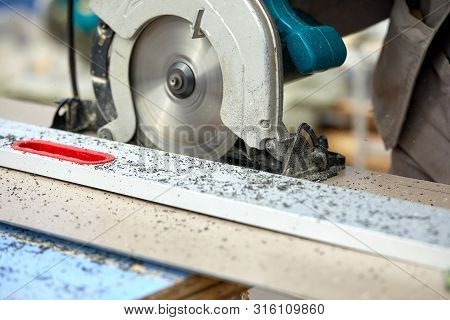 A Construction Contractor Worker Using A Worm-driven Hand-held Circular Saw To Cut Boards And Plasti