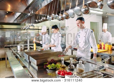 Modern Kitchen. Cooks Prepare Meals On The Stove In The Kitchen Of The Restaurant Or Hotel. The Fire