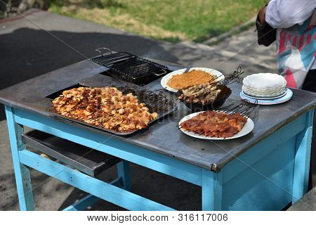 Table With A Small Pieces Of Pork Meat Raw And Grilled On A Skewers In The Taesongsan Funfair. Is An