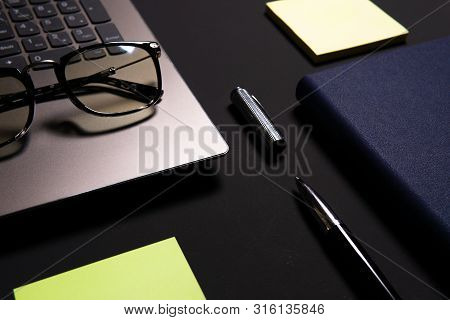 Notebook, Laptop, Glasses And Pen On The Table.