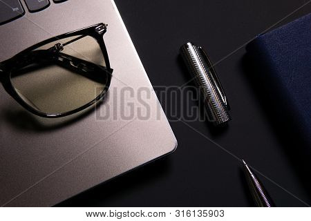 Notebook, Laptop, Glasses And Pen On The Table.