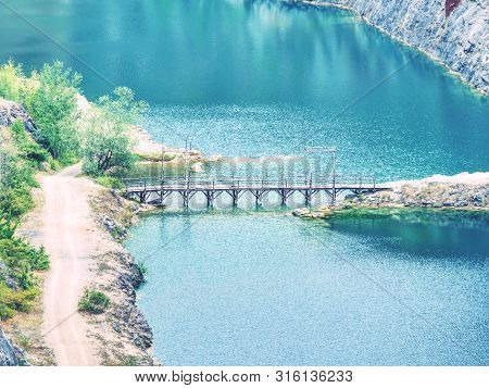 Deep Grand Canyon With Blue Lake At Bottom.  Many Roads Ands At Small Bridge In Middle