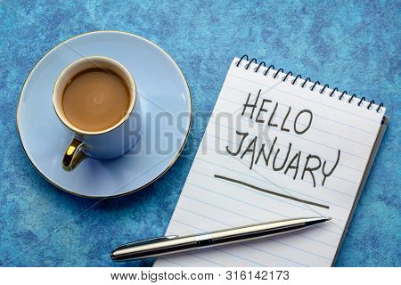 Hello January - handwriting in a notebook with a cup of coffee