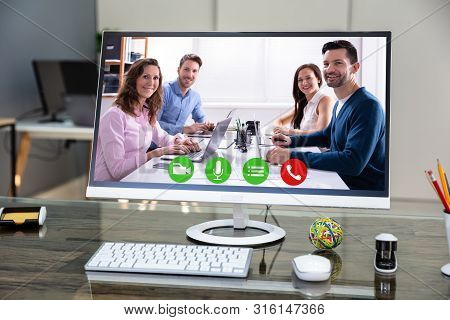Computer Desktop Showing Videoconferencing Application On Office Desk