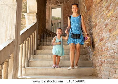 Smiling Young Mother And Daughter Moving Down On Staircase At Palazzo Contarini