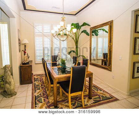 Dining Room With Wooden Table, High Back Chairs And Wall Mirror