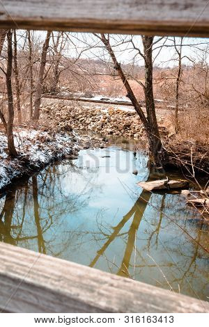 Looking At A Stream Through The Slats Of A Bridge Railing