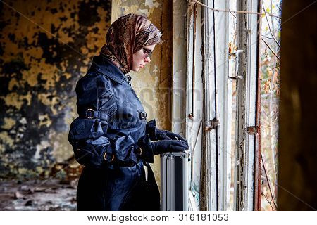 Girl In A Black Cloak, A Scarf And A Diplomat In An Abandoned House Near Window. A Spy In A Secret M