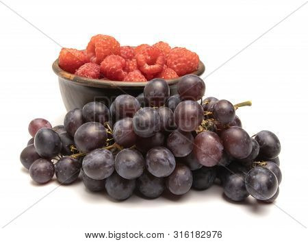 Grapes And Raspberries Lie On A White Background