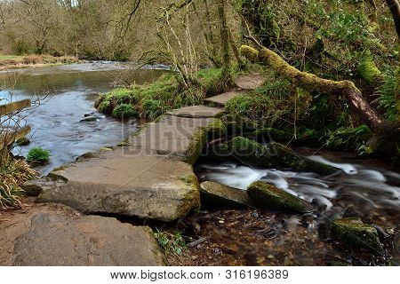 Long Exposure Of The River Flowing Under A Bridge At Tarr Steps In Devon