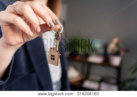 In The Foreground House Key In Womans Hands. Young Pretty Woman. Modern Light Lobby Interior. Real E