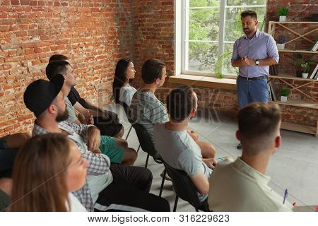 Male Speaker Giving Presentation In Hall At University Workshop. Audience Or Conference Hall. Rear V