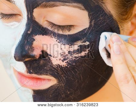 Woman With Clay Carbo Black Mask On One Half Face And White Mud On Second Half. Girl Removing Cosmet