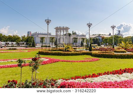 Moscow, Russia - July 22, 2019: Green Lawn Decorated By Flowers Against Pavilions In Vdnh Park In Mo