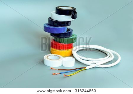Set Of Multicolored Insulating Tapes And White Cable On Gray Background