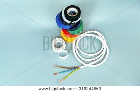 Set Of Multicolored Insulating Tapes And White Cable On Gray Background