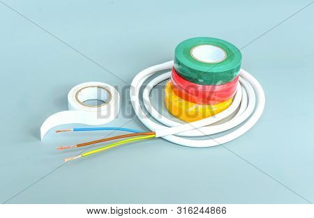 Set Of Multicolored Insulating Tapes And White Cable On Gray Background