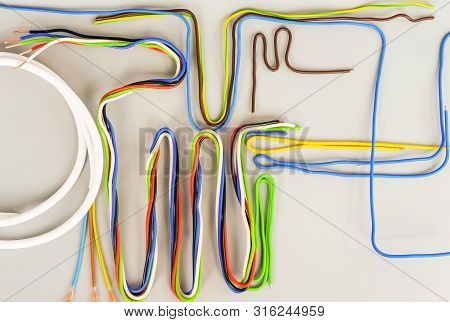 The Wires Of Several Types In Colored Insulation Are Curved In Different Shapes On A Gray Background