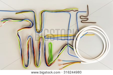 The Wires Of Several Types In Colored Insulation Are Curved In Different Shapes On A Gray Background