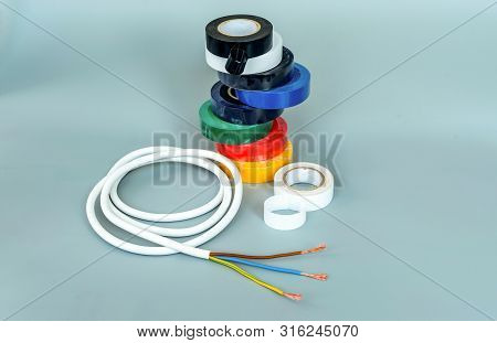 Set Of Multicolored Insulating Tapes And White Cable On Gray Background