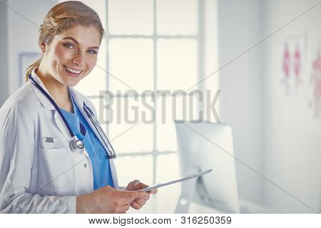 Young Woman Doctor Is Standing With Board With Clipboard Smilin
