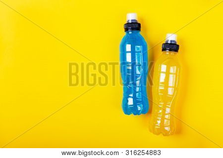 Isotonic Energy Drink. Bottles With Blue And Yellow Transparent Liquid, Sport Beverage On A Colorful