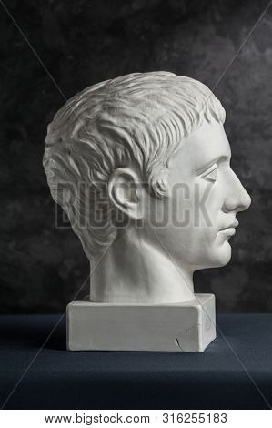 Gypsum Copy Of Ancient Statue Germanicus Head On Dark Textured Background. Plaster Sculpture Man Fac