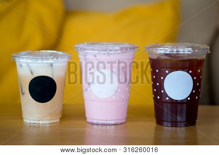 Three Of Iced Drink On Wood Table, Iced Coffee Latte, Iced Pink Milk And Iced Long Black Coffee