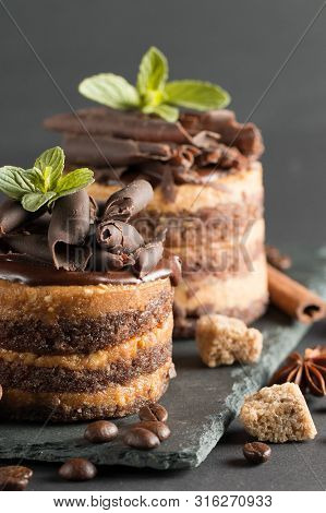 Dark Chocolate Cakes On Black Slattern Board With Mint, Cinnamon, Coffee Beans On A Wooden  Backgrou