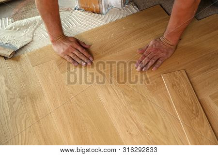 Worker Laying Parquet Flooring. Worker Installing Wooden Laminate Flooring