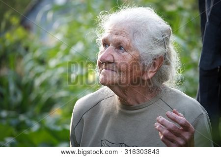 Close-up Portrait Of An Old Woman With Gray Hair Smiling And Looking Up, Face In Deep Wrinkles, Sele