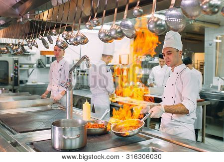 Modern Kitchen. Cooks Prepare Meals On The Stove In The Kitchen Of The Restaurant Or Hotel. The Fire