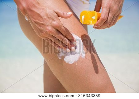 Woman Applying Sunscreen On Leg