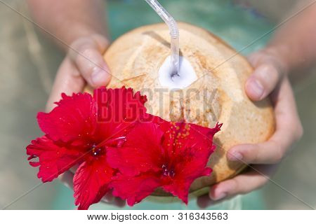 Man Holding A Coconut With Straw And Flower