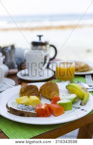 Delicious Healthy Breaklfast Outdoors In A Wooden Table With Sea At Background. The Breakfast Consis
