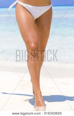 Woman With Fit Legs Running On The Beach In Maldives.