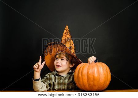 Smiling Boy In Witch Hat With Halloween Pumpkin. Kid With Pumpkin. Halloween Holidays. Trick Or Trea
