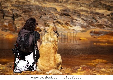 Woman Sitting In The Edge Of Rio Tinto With Her Dog