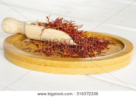 Lot Of Whole Dry Shaffron Thread On Bamboo Plate With Wooden Scoop On White Wood