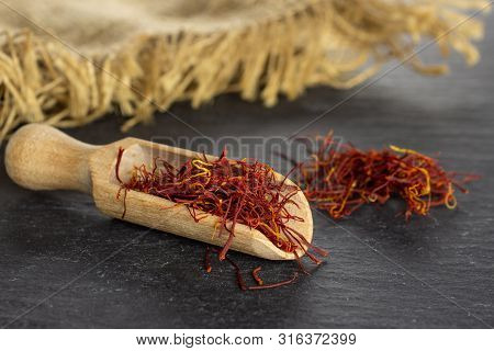 Lot Of Whole Dry Shaffron Thread And Heap Near With Wooden Scoop And Jute Cloth On Grey Stone