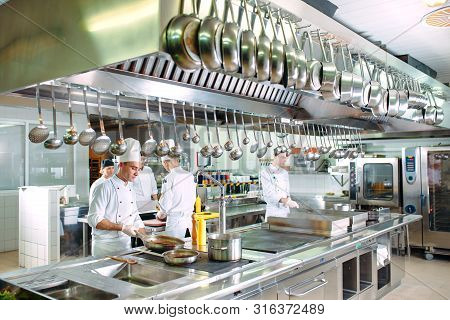Modern Kitchen. Cooks Prepare Meals On The Stove In The Kitchen Of The Restaurant Or Hotel. The Fire