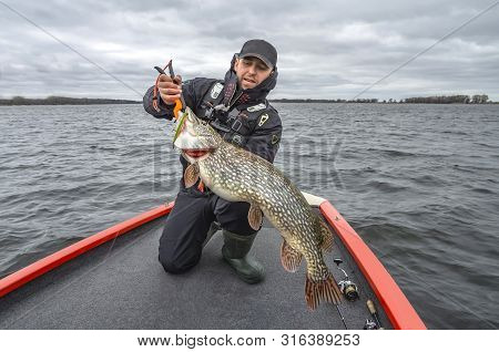 Pike Fishing. Happy Fisherman With Big Fish Trophy At The Boat With Tackles