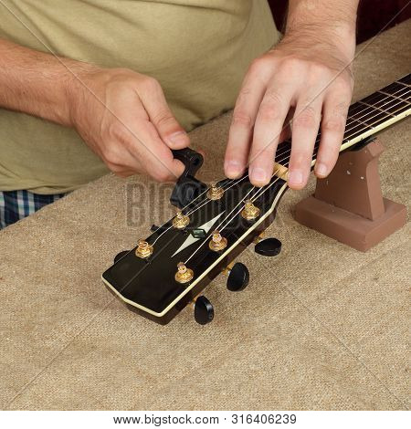 Musical Instrument Guitar Repair And Service - Worker Fix New Strings Black Acoustic Guitar