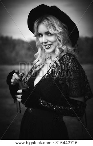 Halloween Theme: Modern Sly Witch In Black Dress And Hat With Mortar And Pestle In Hands. Black And 