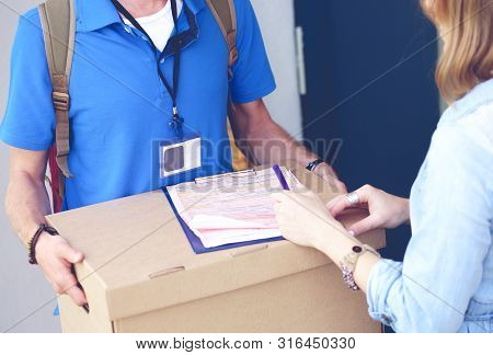 Smiling Delivery Man In Blue Uniform Delivering Parcel Box To Recipient - Courier Service Concept. S