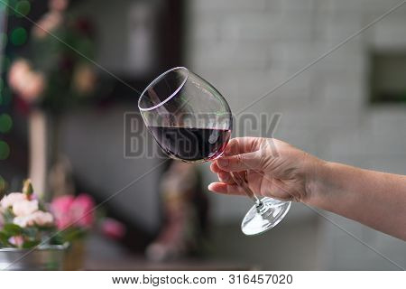 Female Hand Holding Glass With Wine On Blurred Natural Background. Space For Text. Wine Tasting, Res