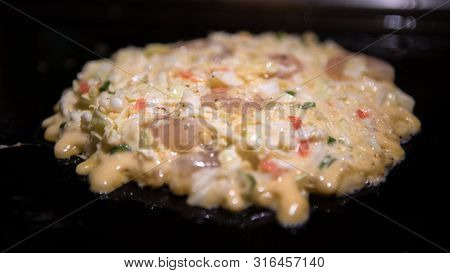 Japanese Food In A Japan Restaurant. Pancake Containing A Variety Of Ingredients, Batter, Made Of Fl