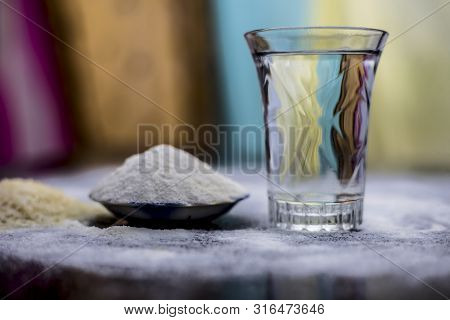 Rice Water In A Glass Bowl Along With Rice Grains & Its Powder Also On Wooden Surface & Some Rice Po