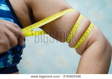 Asian Middle-aged Lady Woman Show Belly Body Fat By Measure Tape Or Line Tape Wearing Sport Pant.