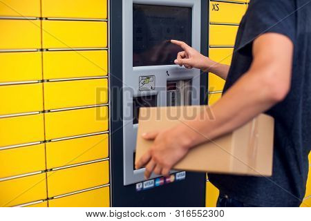 Client Using Automated Self Service Post Terminal Machine Or Locker To Deposit A Parcel For Storage